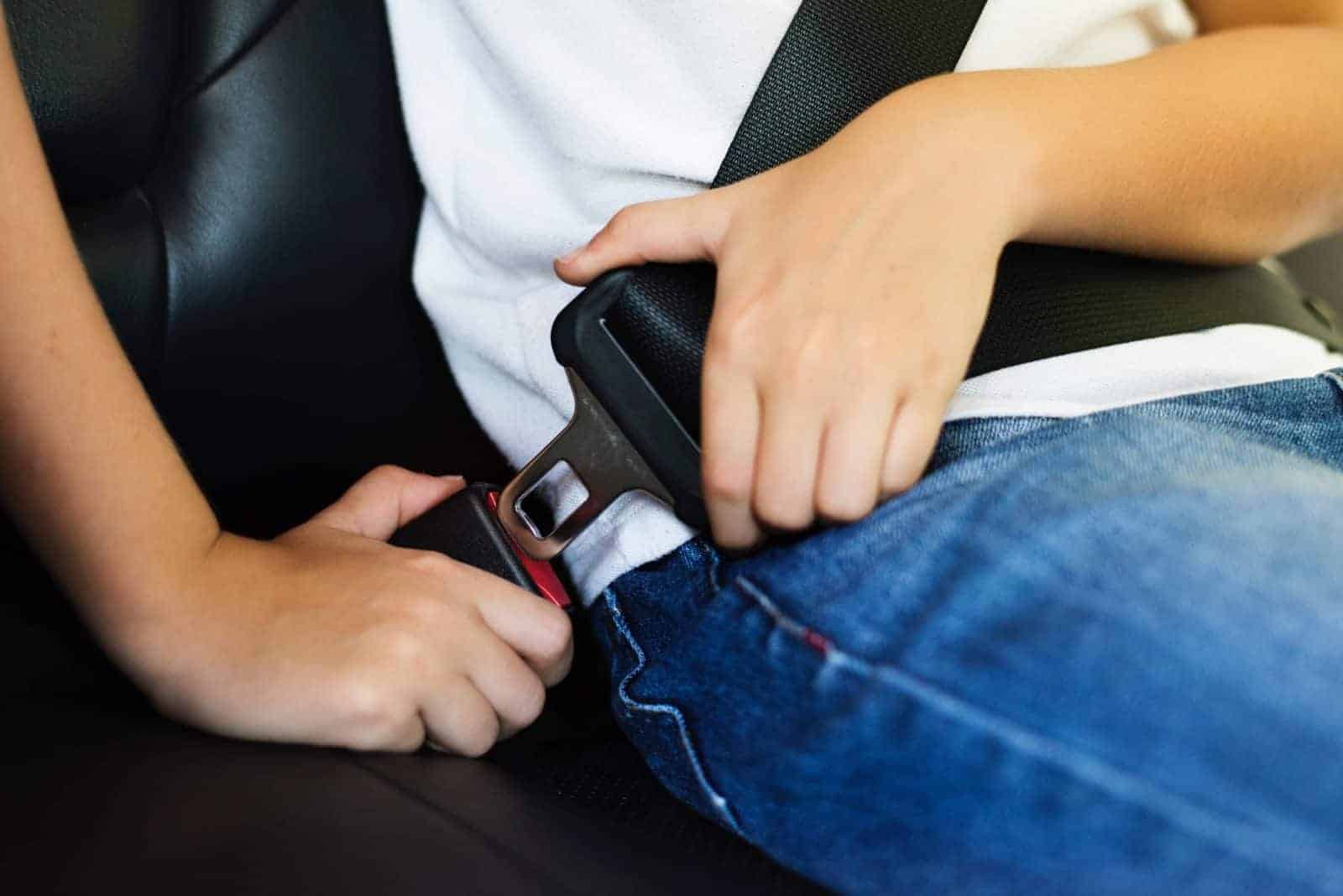 A child putting on a seat belt