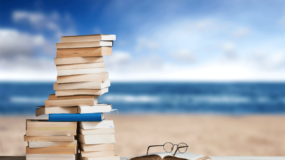 A pile of books about Australia and a pair of glasses on the beach