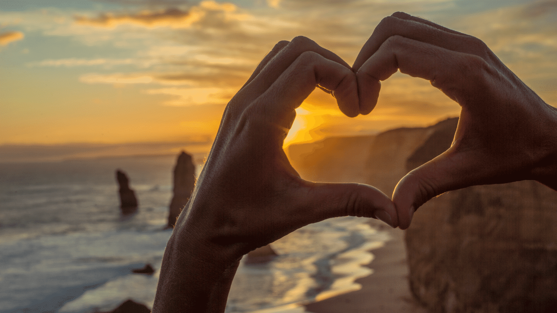 A hand making a heart shape to capture the sunset in Australia