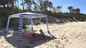 A boy under a CoolCabana on the beach