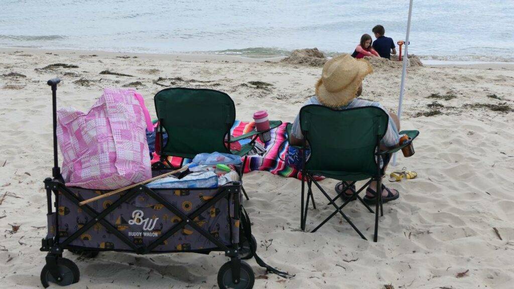 A person living in Australia spending a day at the beach in a chair with lots of beach gear looking out at the ocean