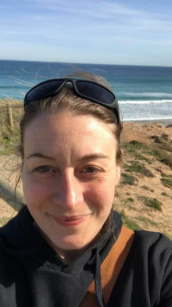 A picture of Gemma standing in front of a beach after she moved to Adelaide