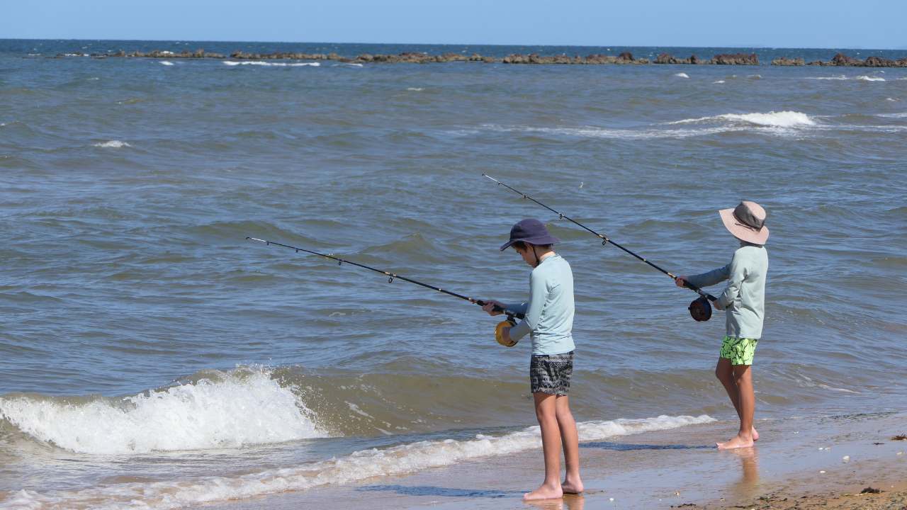 Two kids fishing at the beach in Australia