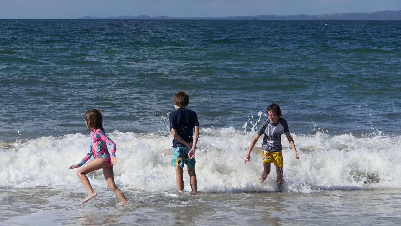 Kids staying sun safe in Australia in the ocean with rash vests on